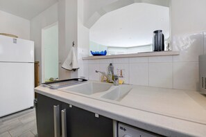 A modern kitchen with a double sink, stainless steel appliances, and a backsplash with a blue decorative piece.
