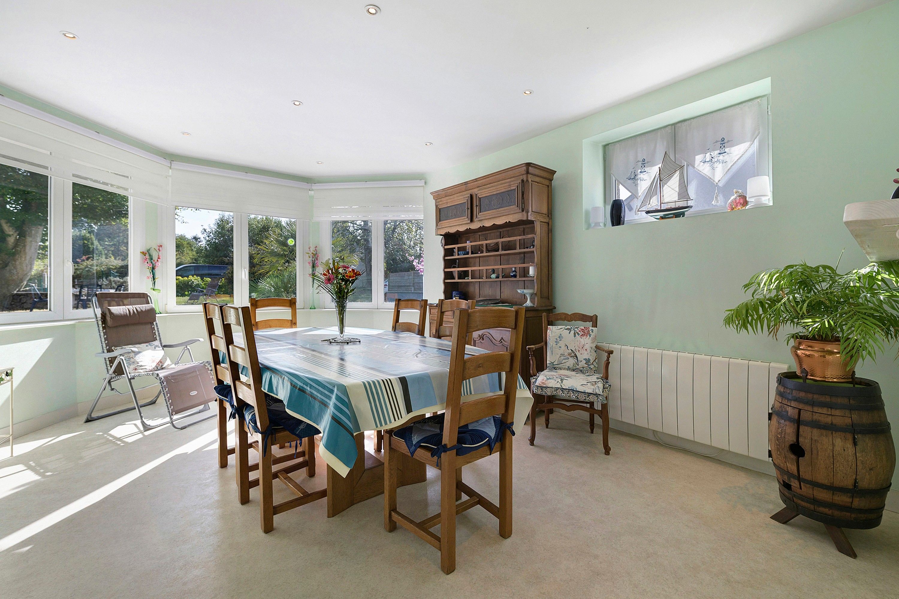 Une salle à manger avec une table dressée pour quatre personnes, entourée de chaises en bois.