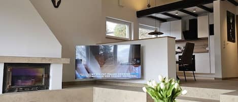 Una sala de estar moderna con chimenea, un televisor de pantalla plana y un jarrón de flores.