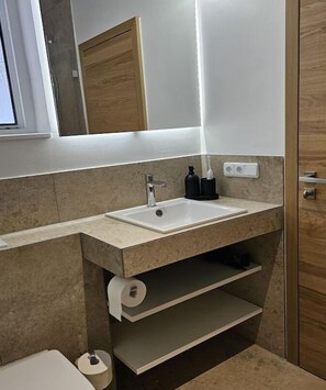 A bathroom with a sink, mirror, and shelves.