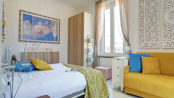 Una habitación de hotel con cama, escritorio, sofá y ventana con cortinas.