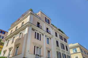 Un edificio de varios pisos con un estilo arquitectónico clásico, que presenta balcones con barandales de metal y molduras decorativas.