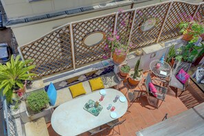 Un patio al aire libre con una mesa redonda, sillas y plantas en macetas.