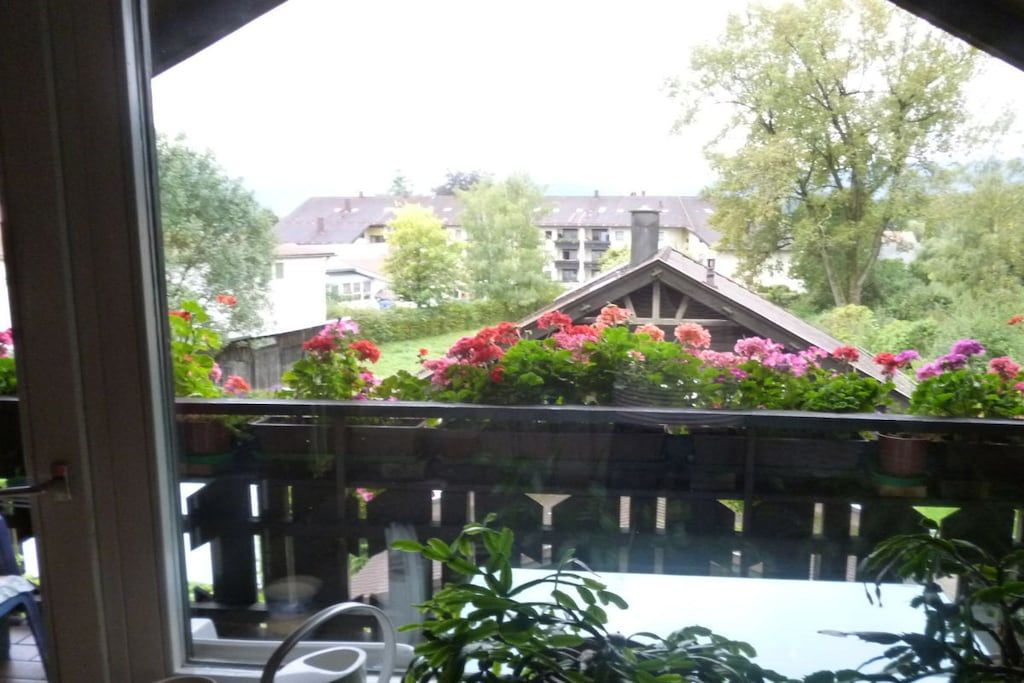 A view from a balcony with a wooden fence, a table, and potted plants.