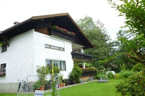 A white building with a balcony, surrounded by greenery and potted plants. - Holiday apartment with 1 bedroom (Sonthofen)