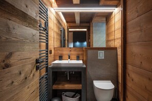 Casa de banho compacta em madeira, com lavatório, sanita e uma pequena janela.