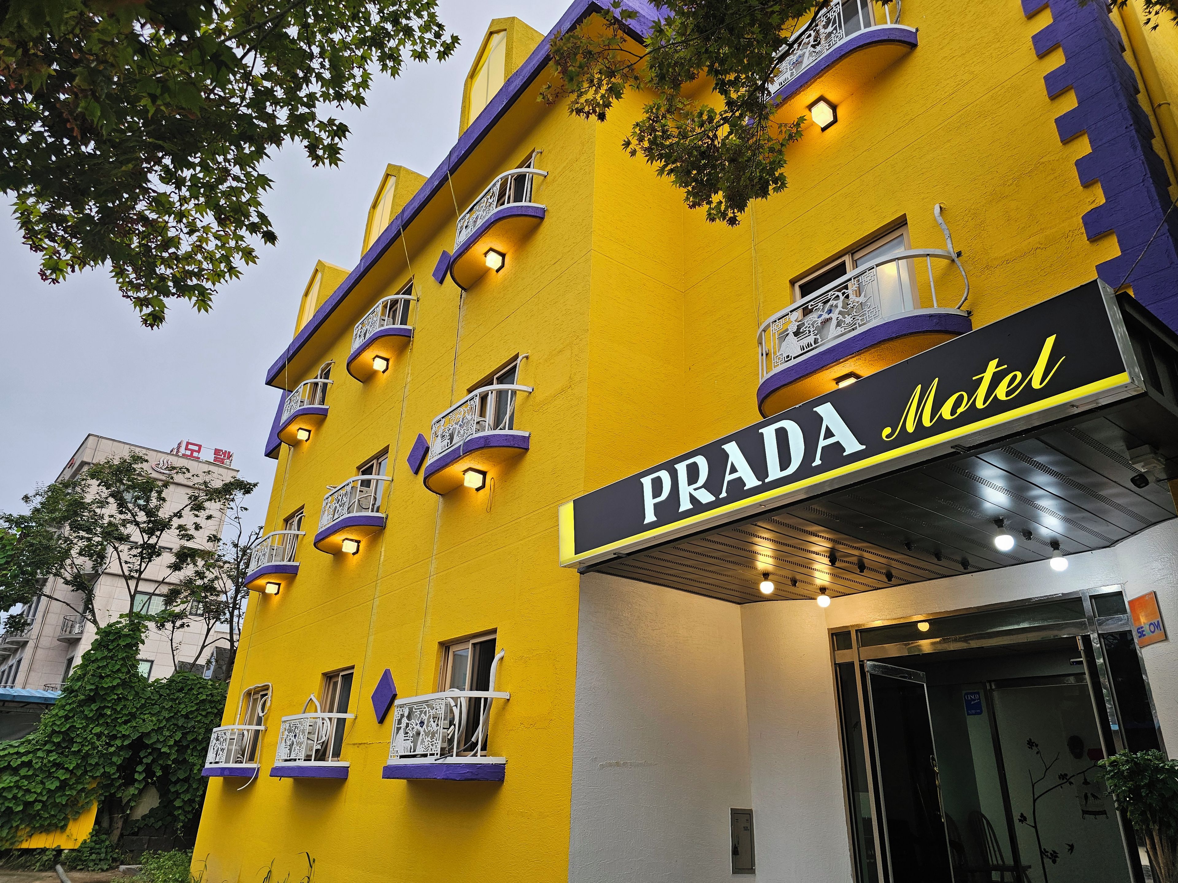 A building with a yellow facade and a sign reading 'PRADA Hotel.'