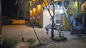 Un edificio con facciata gialla, posti a sedere all'aperto e un gatto a terra.