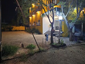 A building with a yellow facade, outdoor seating, and a cat on the ground. - Prada Motel (Yangpyeong-gun)