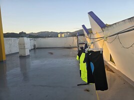 Una terraza con suelo de hormigón, un tendedero con ropa y vistas a montañas distantes.