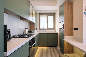 A compact kitchen with a gas stove, kettle, and modern appliances. - Vega, Modern 2br, Best Loc (Istanbul)