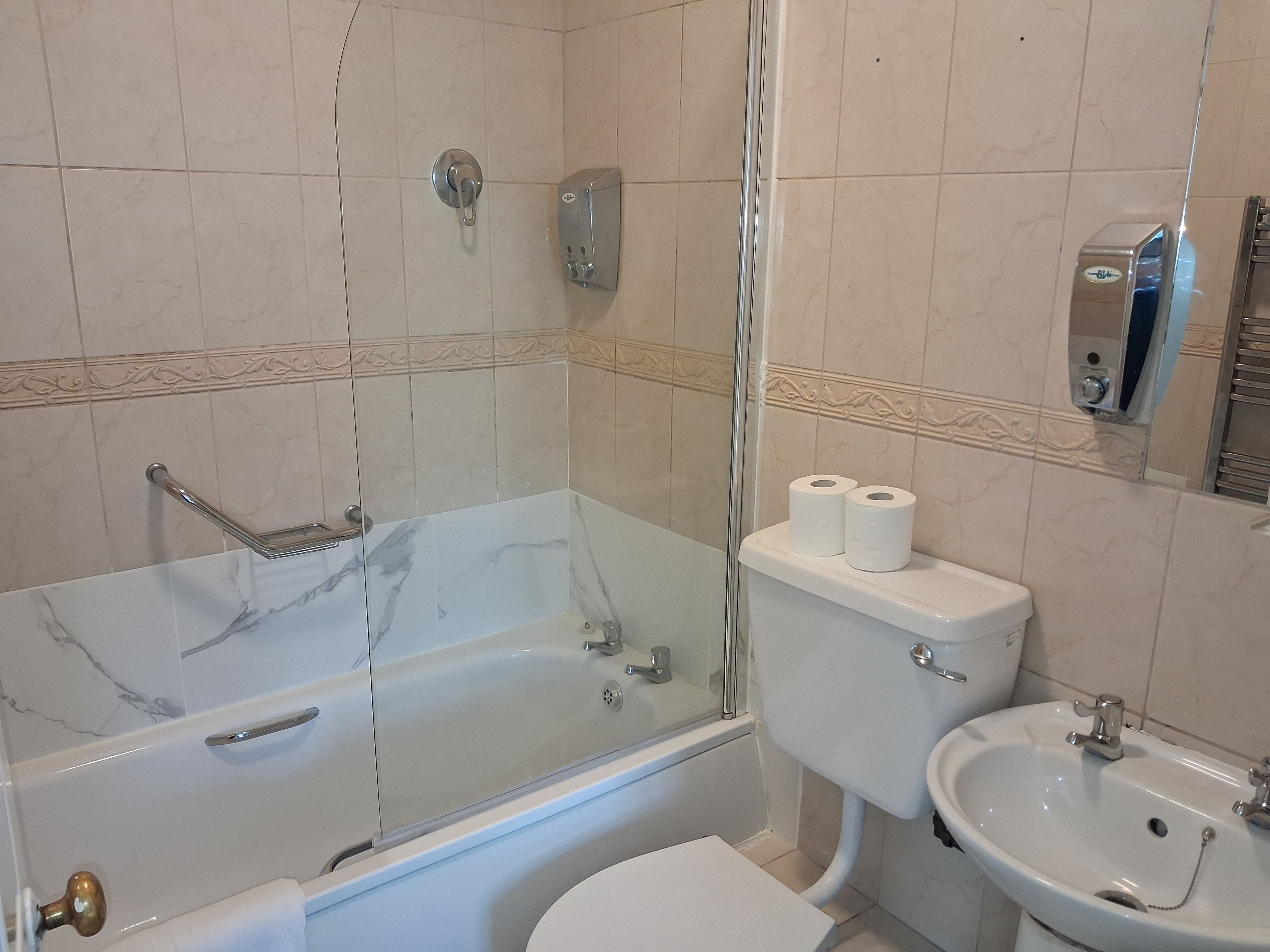 Un baño con ducha separada por vidrio, inodoro y lavamanos.