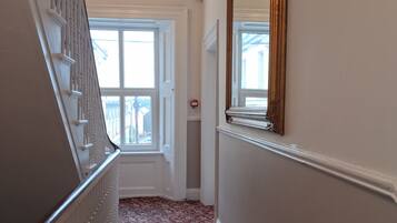 Ein Flur mit einer Treppe, einem großen Spiegel und einem Fenster.