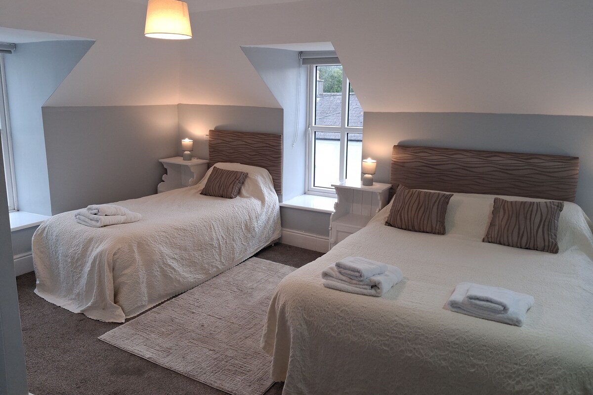 Un dormitorio con dos camas, una ventana y una lámpara.