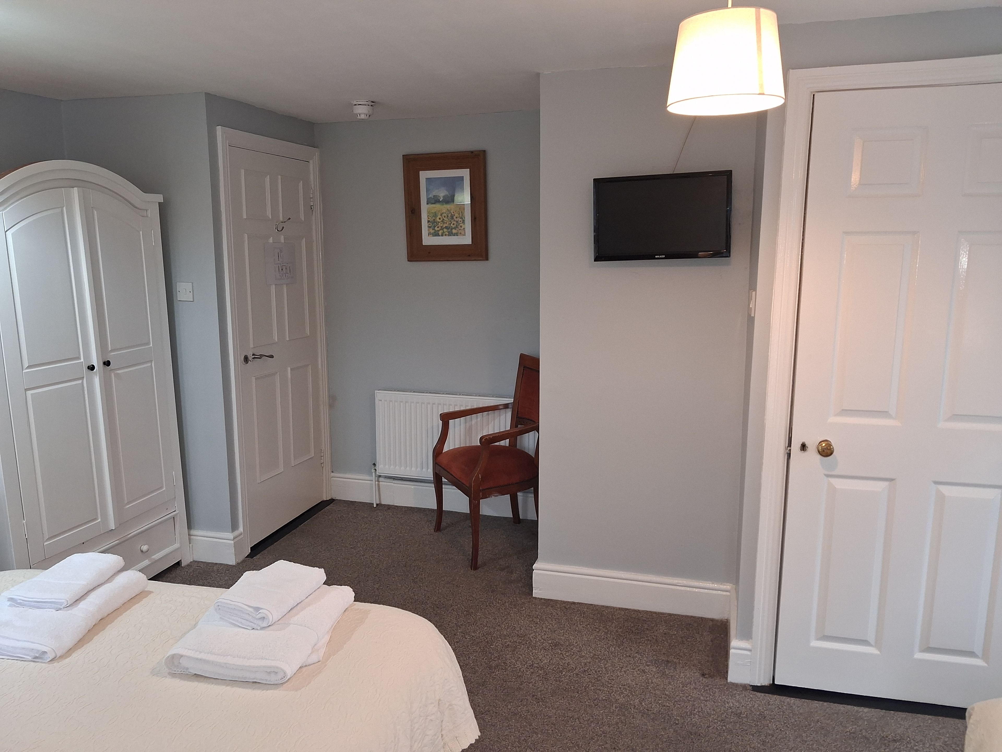 Una habitación de hotel con una cama, una silla, un televisor y un armario.