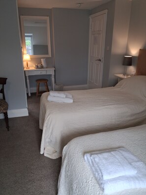 Een slaapkamer met twee bedden, een bureau, een stoel en een spiegel.