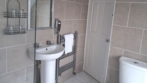 A bathroom with a white sink, mirror, towel rack, and a white toilet. - Tynte House B&B (Dunlavin)