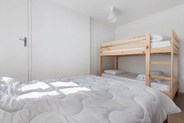 A bunk bed with a white mattress and pillows, a white door, and a ceiling light fixture. - Le Refuge de l’Impératrice Apartment with Mountain View and Wi-Fi (Luz-Saint-Sauveur)