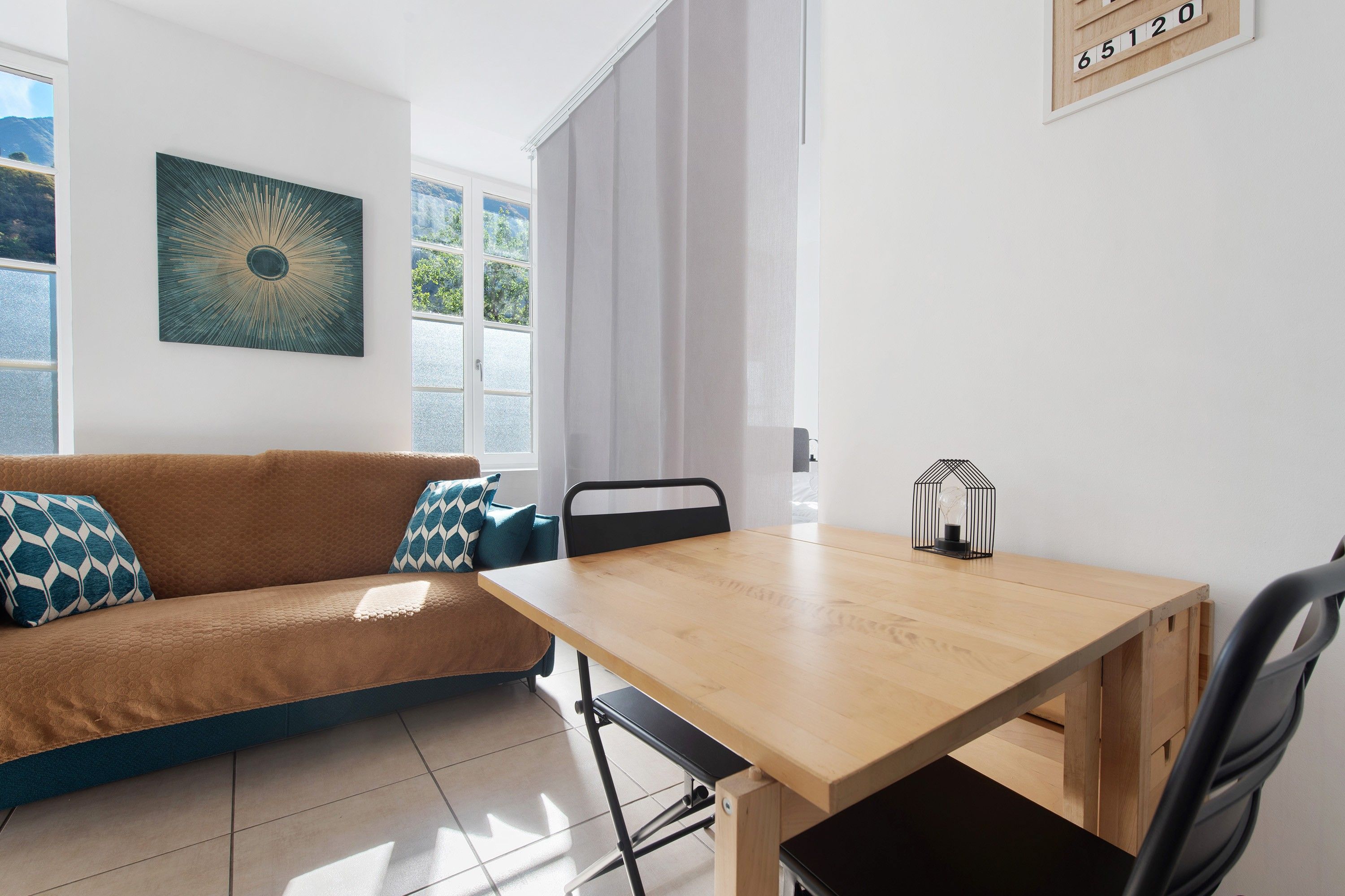 Un salon moderne avec un canapé marron, une table à manger en bois et une chaise noire.