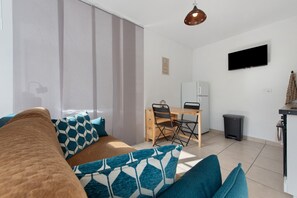 A modern living space with a sofa, a dining table, and a TV mounted on the wall. - Le Refuge de l’Impératrice Apartment with Mountain View and Wi-Fi (Luz-Saint-Sauveur)