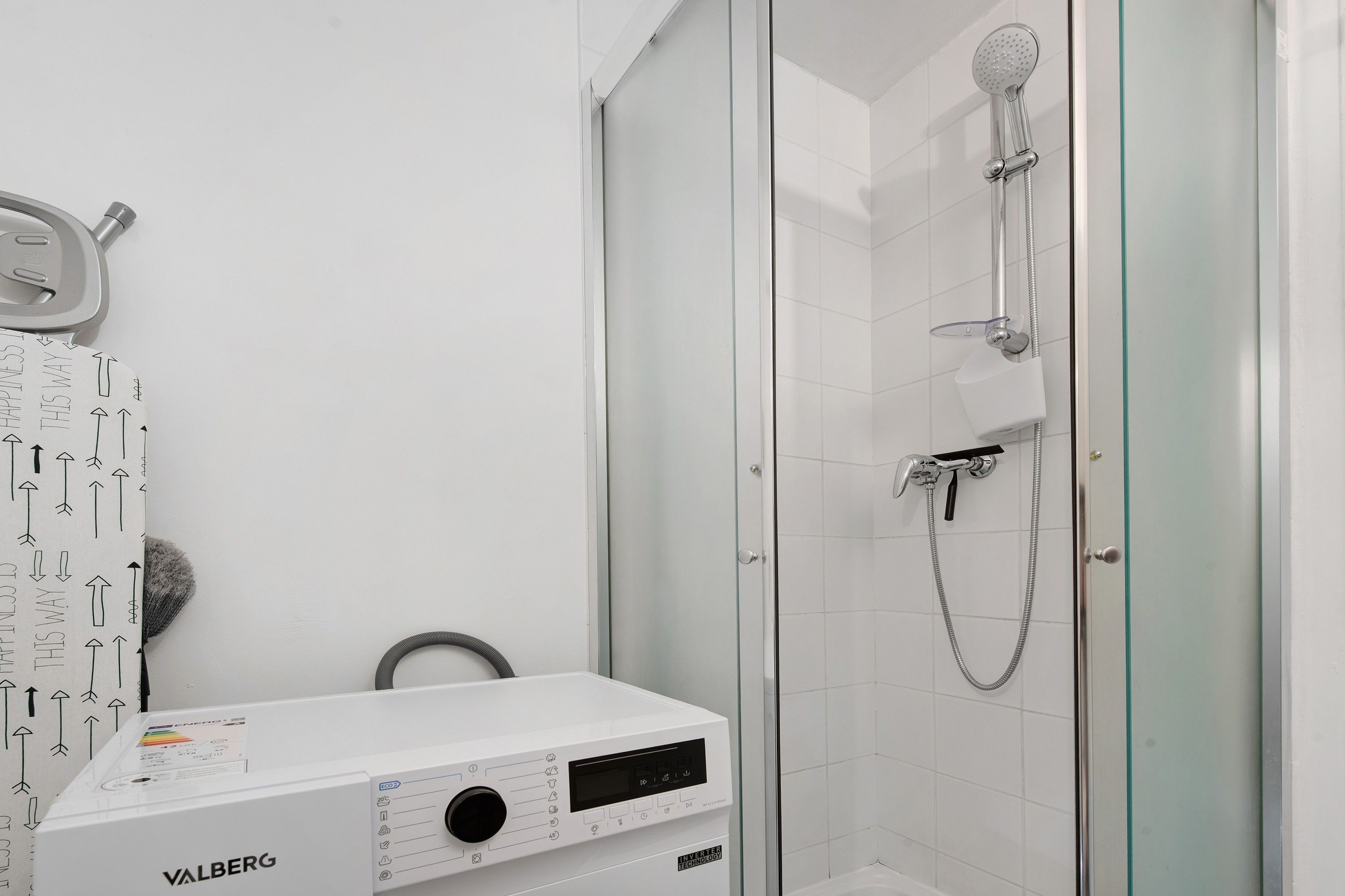 Un baño moderno con cabina de ducha de vidrio, ducha de mano y grifo empotrado.
