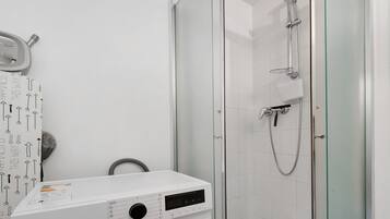 Un baño moderno con cabina de ducha de vidrio, ducha de mano y grifo empotrado.