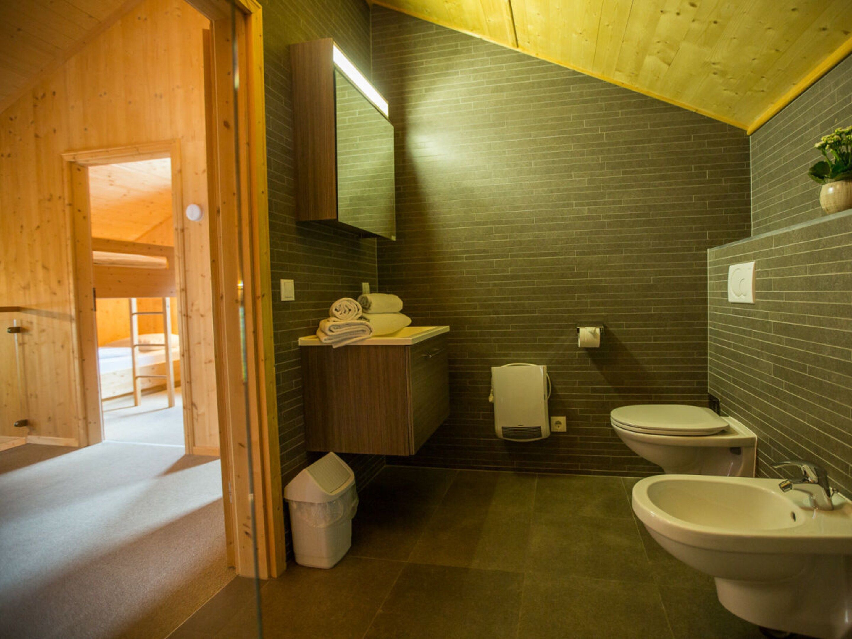 A bathroom with a wooden ceiling, a sink, a bidet, and a toilet.