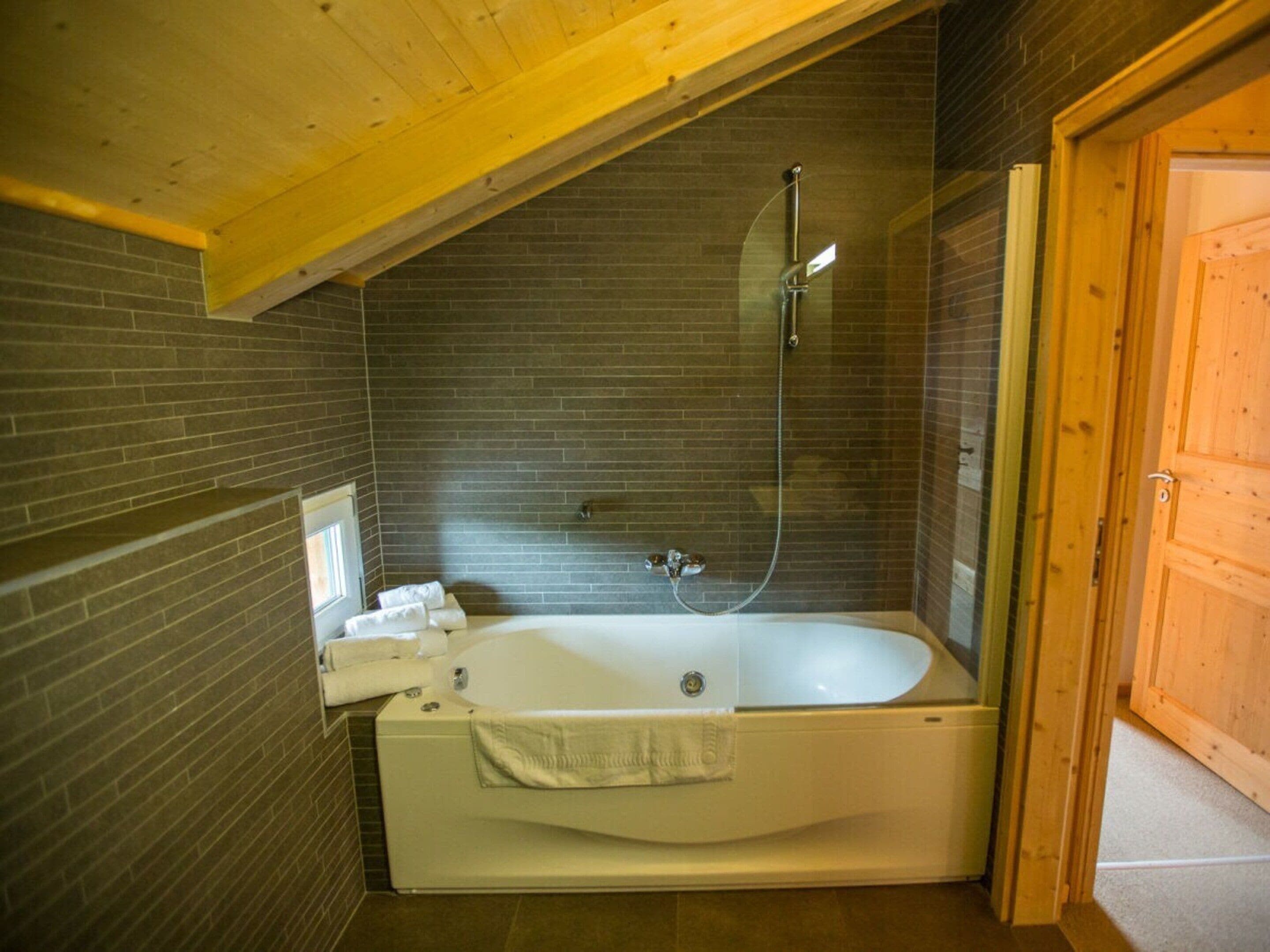 Une salle de bain avec une baignoire, une douche et une porte en bois.
