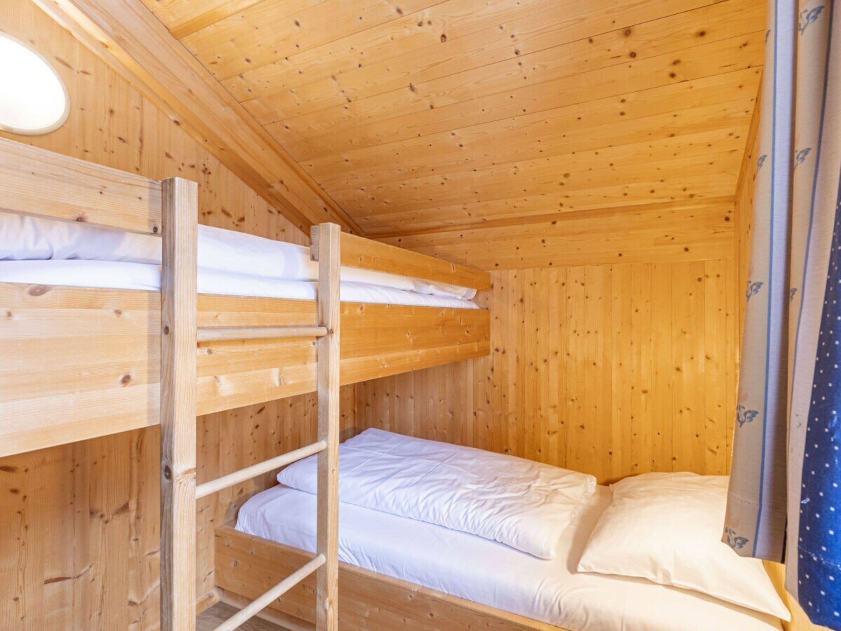 Een slaapkamer met stapelbed, houten wanden en een dakraam.