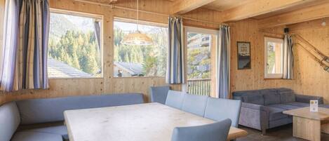 A wooden interior with a dining table, benches, and a sofa.