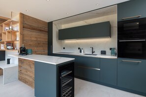 Une cuisine moderne dotée d’un plan de travail en marbre, d’appareils électroménagers intégrés et d’éléments décoratifs en bois.