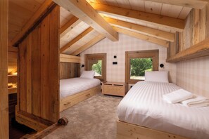 Une chambre de style cabane en bois, avec deux lits simples, une fenêtre et une banquette intégrée.