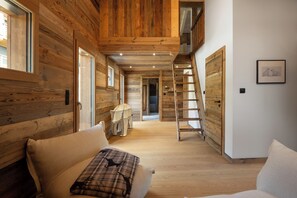 A wooden interior with a sofa, a ladder, and a framed picture on the wall. - ✨ Le Refuge de Lola – Family Chalet with Hot Tub, Games Room & Fireplace (Gérardmer)