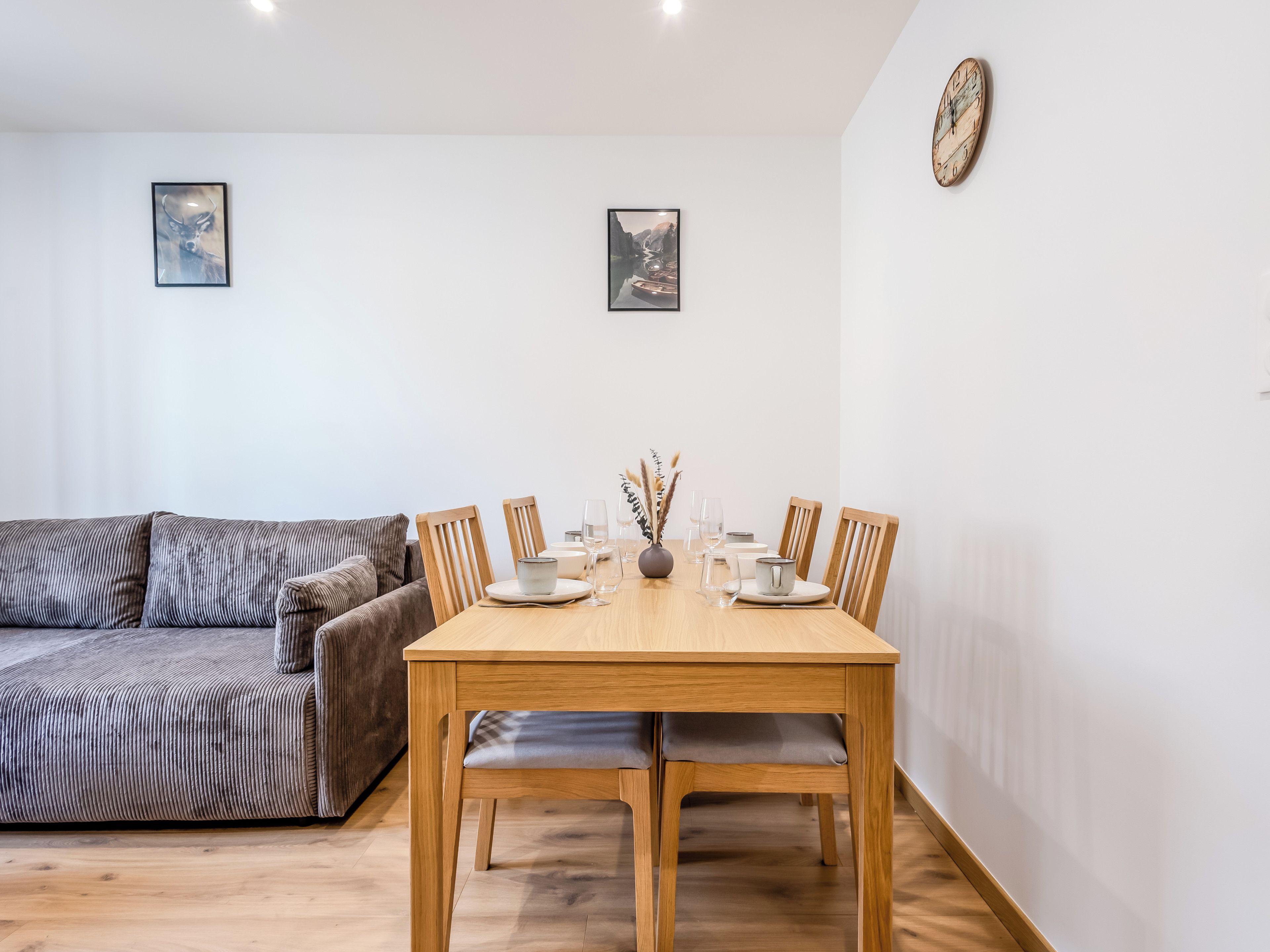 Un comedor con mesa de madera dispuesta para cuatro personas, flanqueada por dos sillas de madera.