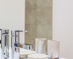 A bathroom with a modern chrome faucet, a mirror, and two marble-like containers on the counter. - Douceur du Lac - Gérardmer, Vosges (Gérardmer)