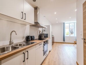 Eine moderne Küche mit Edelstahlgeräten, Holz Arbeitsplatten und Blick ins Freie.