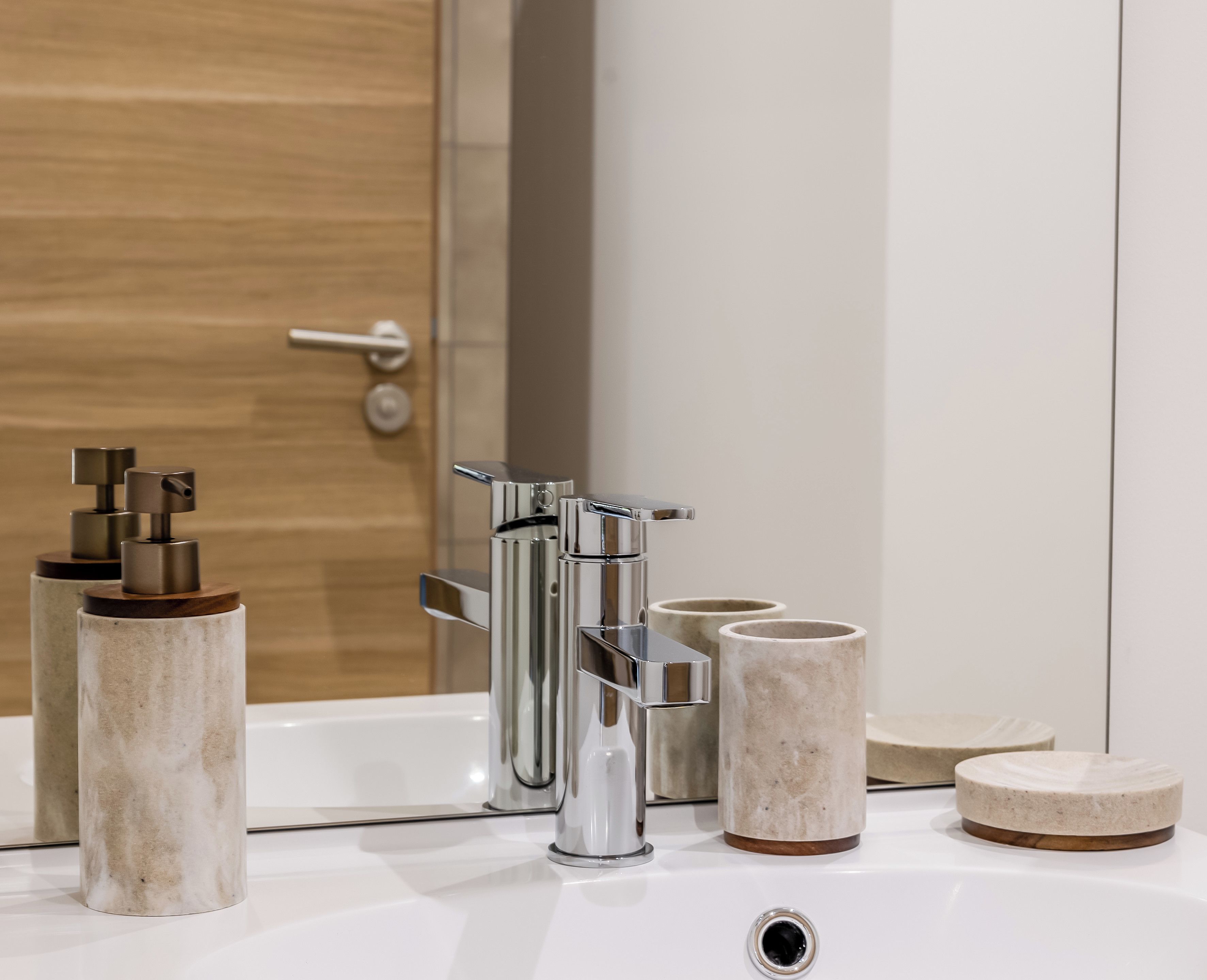 Une salle de bain dotée d’un lavabo moderne, d’un robinet chromé et de récipients cylindriques.