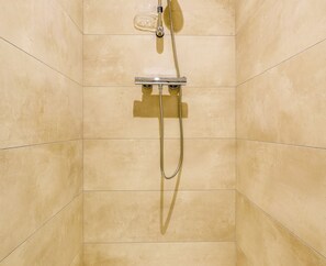 Eine Dusche mit einer Handbrause und einem fest installierten Duschkopf an der Wand.