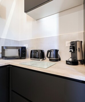 Een moderne keuken met een broodrooster, waterkoker en koffiezetapparaat op het aanrecht.