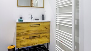 Ein Badezimmer mit einem weißen Waschbecken, einer Holzkommode und einem Spiegel mit goldener Rahmung.