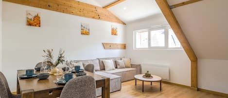 A dining area with a wooden table and chairs, a sofa, and a small coffee table.