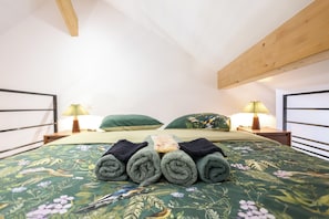 A neatly made bed with rolled towels, a floral bedspread, and two bedside lamps. - Souffle du Lac - Gérardmer, Vosges (Gérardmer)