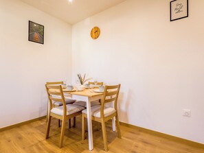 A dining area with a wooden table and chairs, a wall clock, and a framed quote on the wall. - Écume du Lac - Gérardmer, Vosges (Gérardmer)