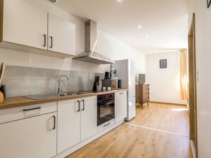 A modern kitchen with white cabinetry, stainless steel appliances, and a wooden countertop. - Écume du Lac - Gérardmer, Vosges (Gérardmer)
