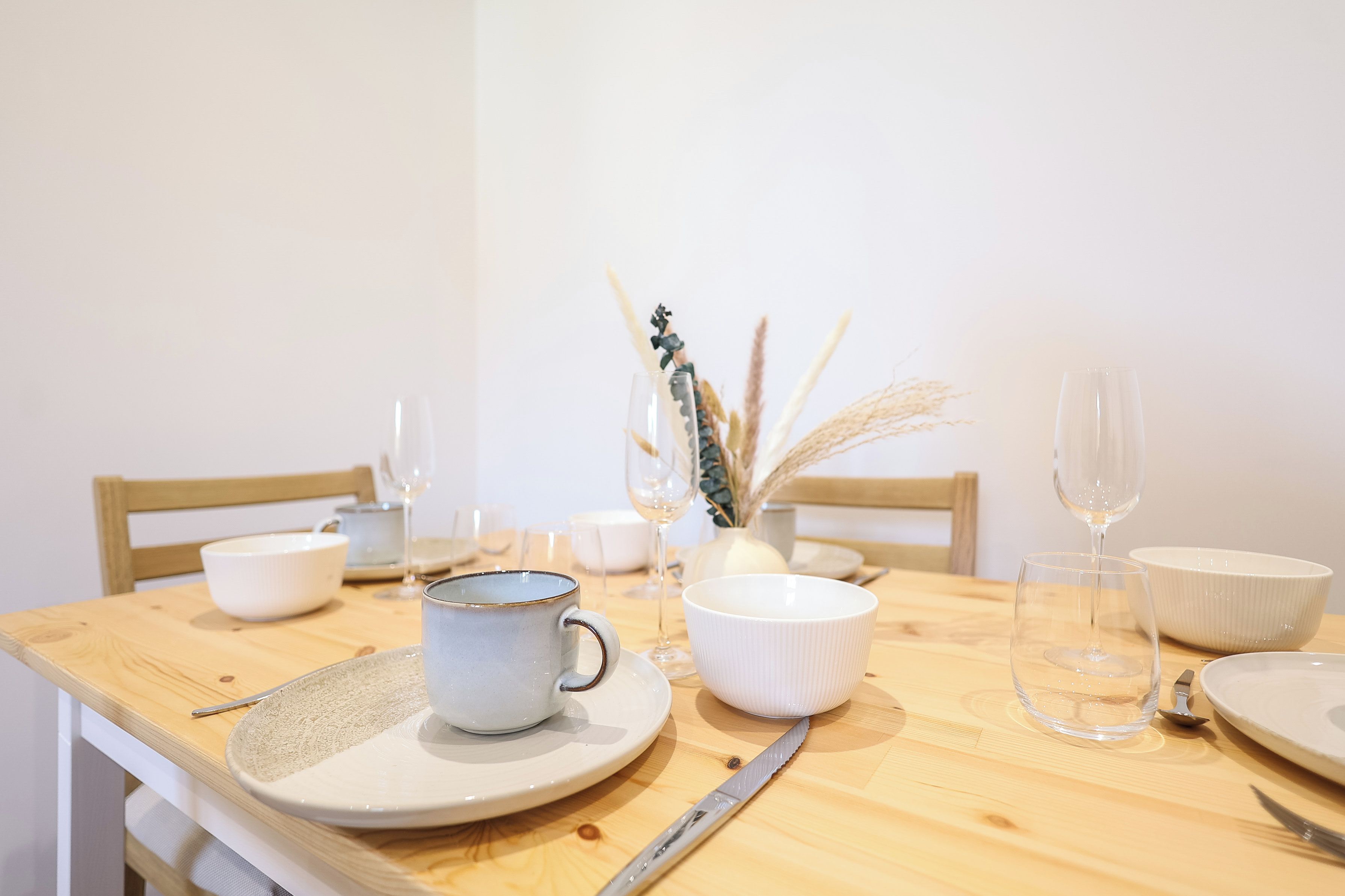 A dining table with white ceramic plates, cups, and a knife.