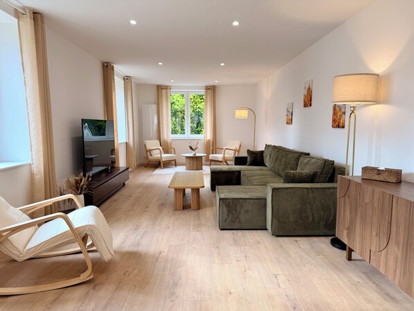 Una sala de estar moderna con un sofá, sillones, un televisor y una lámpara.