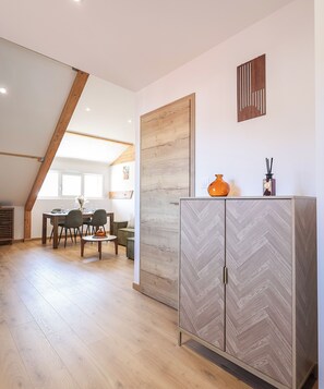Une pièce spacieuse comprenant un coin repas, un meuble aux motifs en chevrons et une porte en bois.