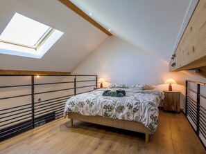 A bedroom with a skylight, a bed with floral bedding, two bedside tables with lamps, and a wooden headboard. - L'Éveil du Lac ★ Downtown • Walk to the Lake • Netflix • Wi-Fi • King Bed (Gérardmer)
