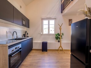A modern kitchen with a built-in oven, a black refrigerator, and a window with a view of the outdoors. - L'Éveil du Lac ★ Downtown • Walk to the Lake • Netflix • Wi-Fi • King Bed (Gérardmer)