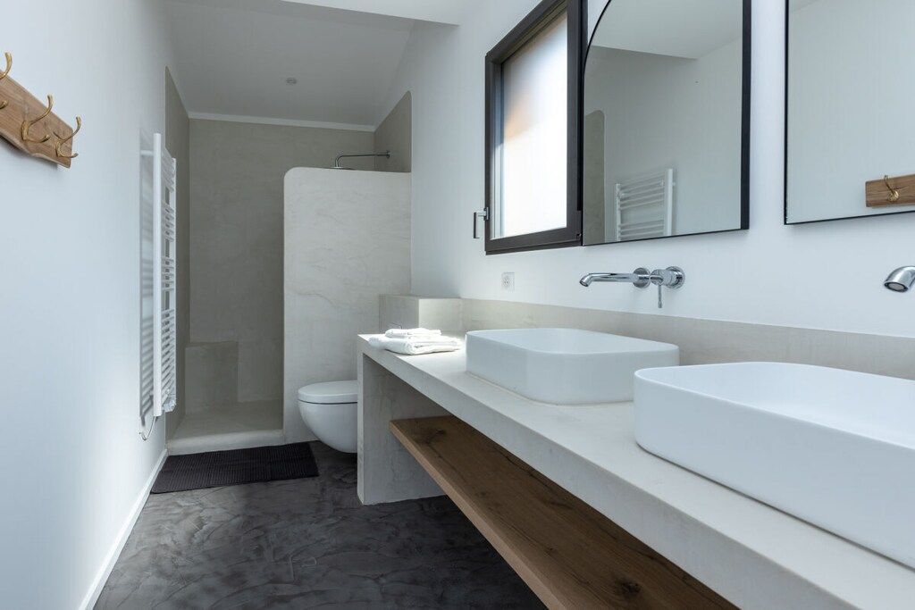 A modern bathroom with a large white sink, a mirror, and a shower enclosure.